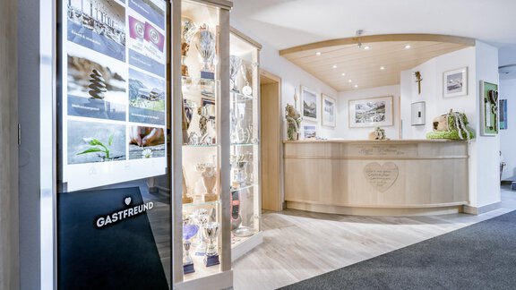 An inviting reception area with a wooden counter and display cases full of awards. In the background are pictures and decorations that create a friendly atmosphere. - Appartementhaus Kathrin - Sölden