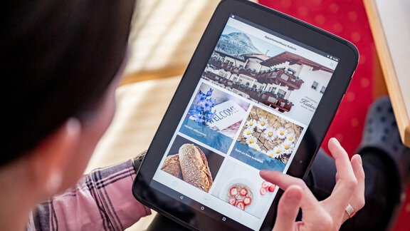 A person is looking at various images on a tablet. The images show accommodation, food, and decorative elements. - Appartementhaus Kathrin - Sölden