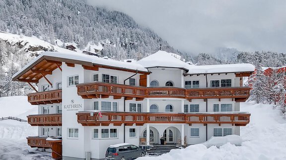 A charming building in alpine style, surrounded by snow-covered landscapes. The sky is overcast, and the surroundings exude tranquility and winter coziness. - Appartementhaus Kathrin - Sölden