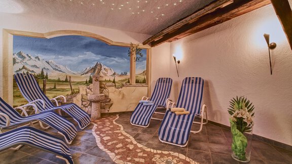 A relaxing space with loungers and a wall mural of mountains. Soft light and a cozy atmosphere create a calm environment. - Belledonne Ski in & out Appartements - Sölden