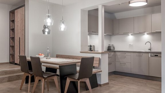 A modern kitchen with a dining area. There is a table with chairs and a bright, open atmosphere. - CORSO living Aparthotel - Sölden