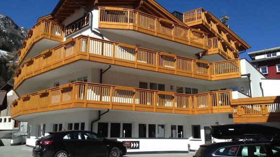 A modern hotel with wooden cladding and several balconies. The building is situated in a mountainous area with a clear sky. - Hotel-Appartements A CASA "Saphir" - Sölden