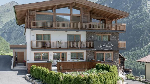 A modern house in Alpine style with wooden cladding and large windows. The surroundings are green and mountainous, ideal for a relaxing holiday. - The Peak Sölden - Sölden
