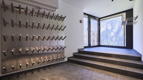 A modern entrance area with lockers on the wall and large windows that let in plenty of daylight. The staircase leads to a bright and inviting room. - The Peak Sölden - Sölden