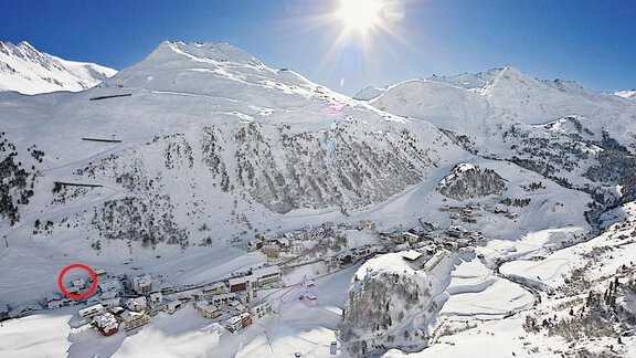 A majestic mountain landscape with snow-covered peaks and a sunny winter atmosphere. In the foreground, there is a small village nestled in the winter landscape. - Haus Verwall Appartements - Obergurgl 