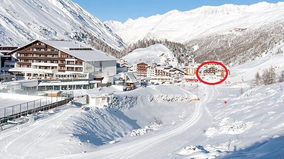 A picturesque snow landscape with mountains in the background. In the foreground, there is a skier on a slope and some buildings are visible. - Haus Verwall Appartements - Obergurgl 