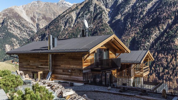 A modern wooden house with a flat roof, surrounded by picturesque mountains. The surroundings are rural and peaceful, perfect for a getaway in nature. - The Peak Sölden - Sölden