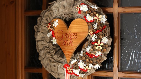 A decorative door wreath made of natural materials with a heart-shaped wooden sign. The sign reads "Grüß euch" and the wreath is adorned with flowers. - Appt.  Ferienglück - Sölden