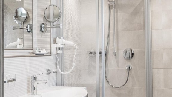 A modern bathroom with a shower and a sink. The walls are bright and the room is well lit. - Garni Ötztal ROOMS & APARTS - Zwieselstein