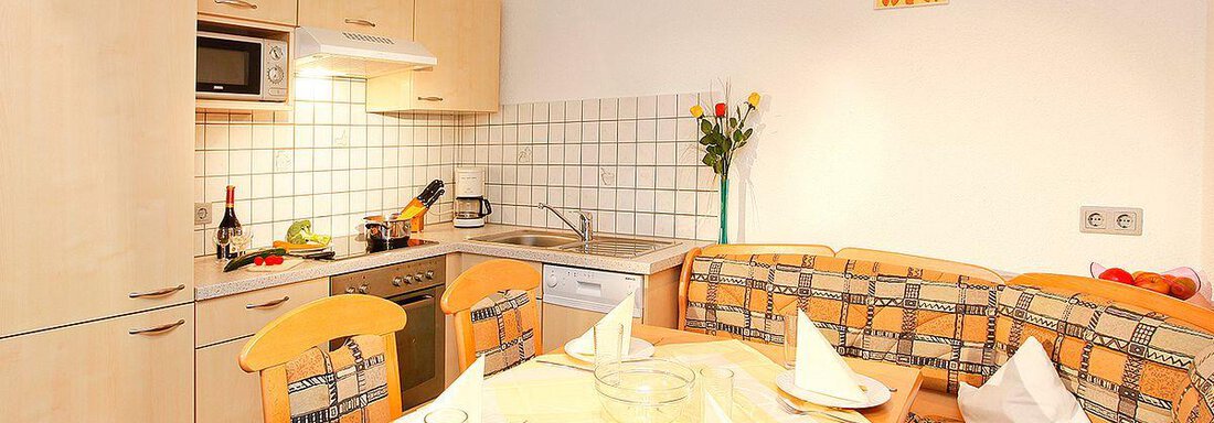 Appt. 2 Küche1 A bright kitchen with a cozy dining area. The table is festively set and there are fresh flowers. - Berghof Schöpf - Gries