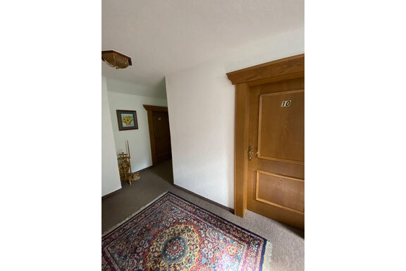 Ein Flur mit einem bunten Orientteppich und Holzdetails. Die Tür mit der Nummer 10 ist gut sichtbar. - Haus Bergkristall - Gries