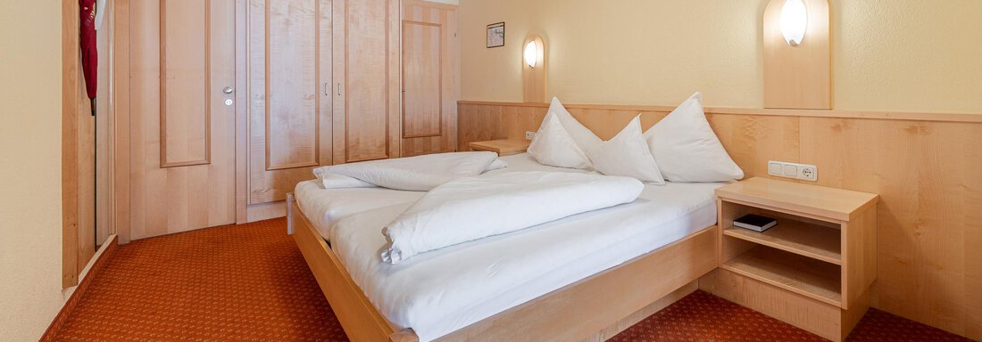 Ein einfaches, gemütliches Hotelzimmer mit zwei Einzelbetten und Holzverkleidung. Die Wände sind in warmen Gelbtönen gestrichen. - Hotel Schöpf - Gries