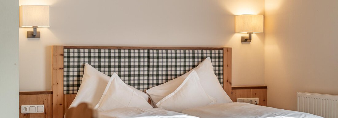Ein gemütliches Schlafzimmer mit zwei Betten und einem Holzrahmen. Weiche Kissen und sanfte Beleuchtung schaffen eine einladende Atmosphäre. - Hotel Schöpf - Gries