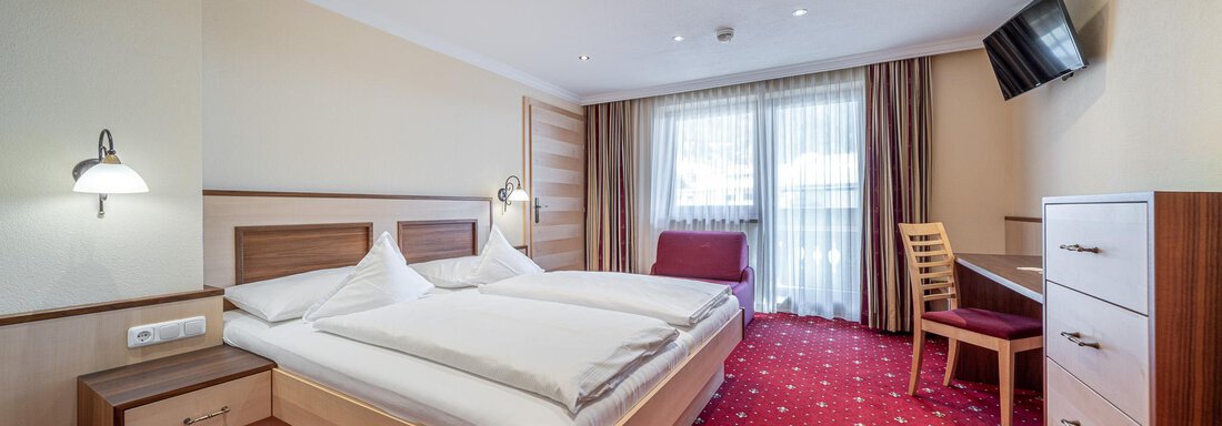 Zimmer (Familienzimmer 210) 8 Ein gemütliches Hotelzimmer mit zwei Einzelbetten und einem Fenster, das viel Tageslicht hereinlässt. Im Zimmer befinden sich ein Schreibtisch, ein Stuhl und ein Fernseher. - Hotel Schöpf - Gries