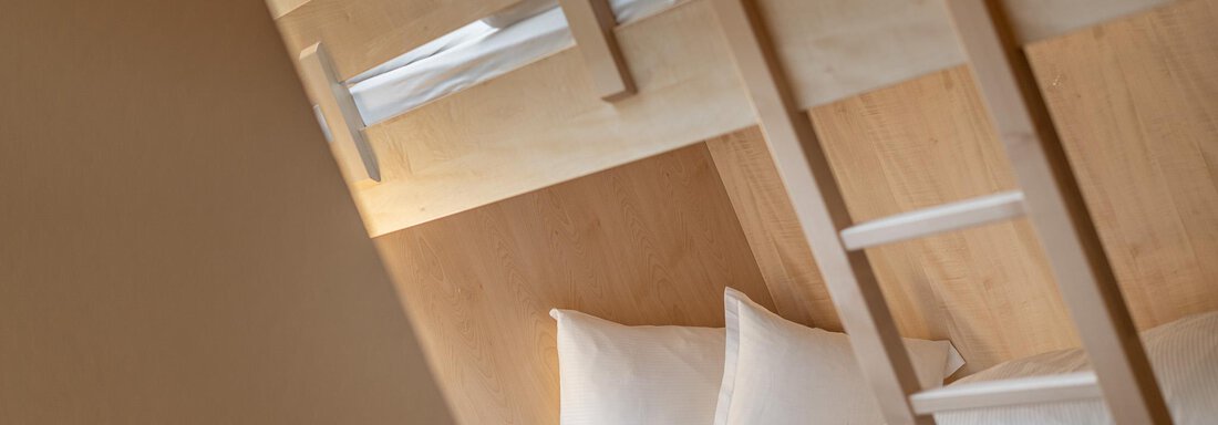 Ein schlichtes Kinderzimmer mit einem Etagenbett aus Holz. Die Bettwäsche ist ordentlich und die Umgebung ist hell und freundlich. - Hotel Schöpf - Gries