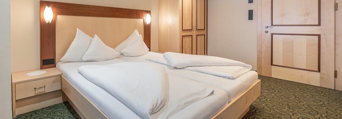 Ein gemütliches Schlafzimmer mit einem Doppelbett und geschmackvoller Einrichtung. Der Teppich ist grün und die Wände sind in neutralen Farben gehalten. - Hotel Schöpf - Gries