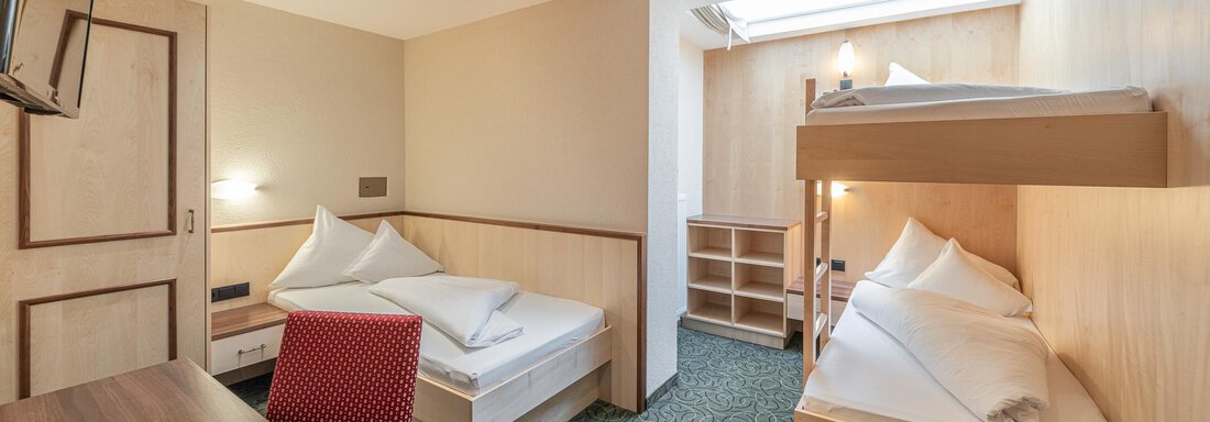 Ein einfaches Zimmer mit zwei Betten und einem Etagenbett. Helle Wände und ein grüner Teppich sorgen für eine gemütliche Atmosphäre. - Hotel Schöpf - Gries