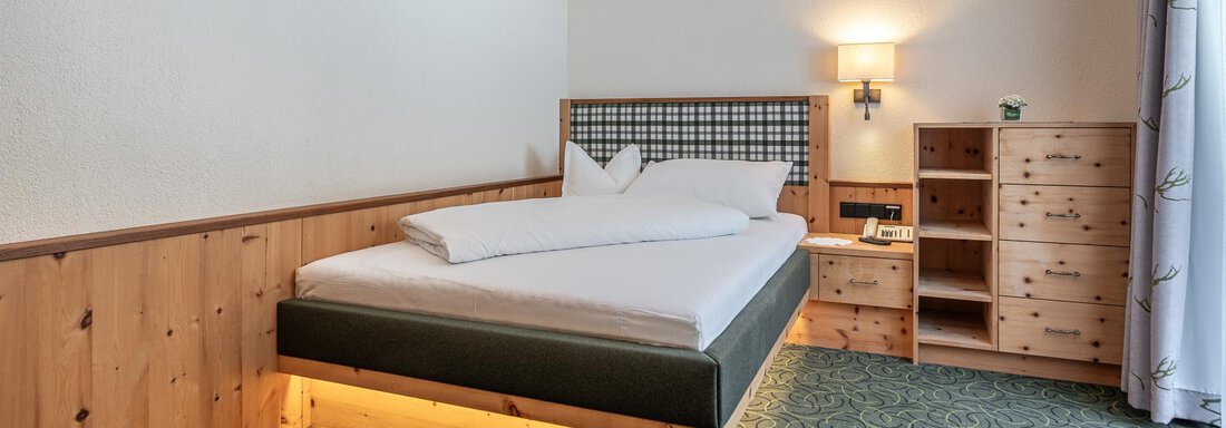 Zimmer (Einzelzimmer Suite 301) 6 Ein modernes Schlafzimmer mit einem großen Bett und Holzmöbeln. Die Wände sind hell, und der Teppich hat ein grünes Muster. - Hotel Schöpf - Gries