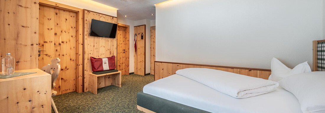 Ein modernes Hotelzimmer mit Holzvertäfelung und einem gemütlichen Bett. Der Raum hat eine entspannte Atmosphäre und ist gut beleuchtet. - Hotel Schöpf - Gries