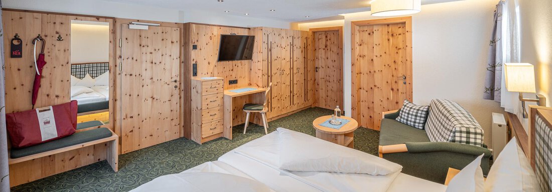 Ein gemütliches Hotelzimmer mit Holzwänden und zwei Einzelbetten. Der Raum ist hell und hat eine Sitzecke mit einem Tisch. - Hotel Schöpf - Gries