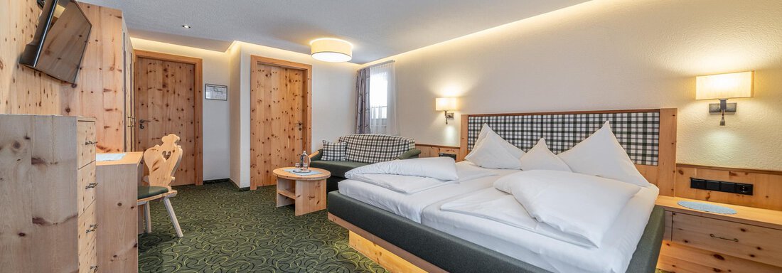 Ein gemütliches Hotelzimmer mit einem großen Doppelbett und Holzmöbeln. Das Zimmer ist hell und modern eingerichtet, mit einem Fernseher und einem kleinen Tisch. - Hotel Schöpf - Gries