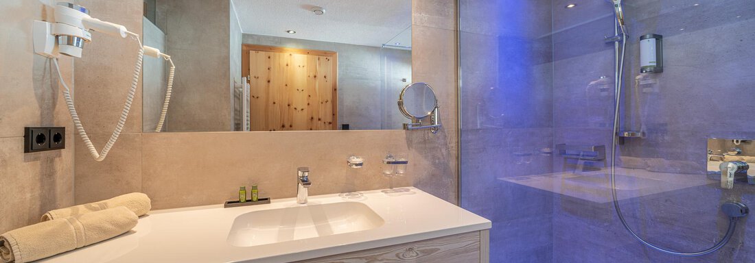 Ein modernes Badezimmer mit einer großen Dusche und einem eleganten Waschbecken. Die Wände sind in neutralen Farben gehalten und es gibt eine angenehme Beleuchtung. - Hotel Schöpf - Gries