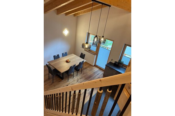 A modern dining room with a large wooden table and black chairs. Bright walls and large windows create a friendly atmosphere. - KLAMMERHOF - Gries