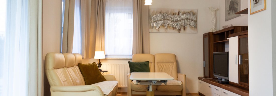 Foto-2 Ein helles Wohnzimmer mit bequemen Sesseln und einem Tisch. Große Fenster sorgen für viel Licht und eine gemütliche Atmosphäre. - Ferienhaus Neurauter - Haiming