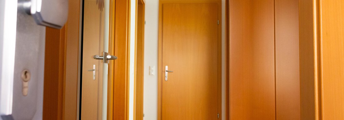 Ein heller Flur mit Holzdekor und geschlossenen Türen. Die Wände sind neutral gehalten und es gibt einen Spiegel. - Ferienhaus Neurauter - Haiming