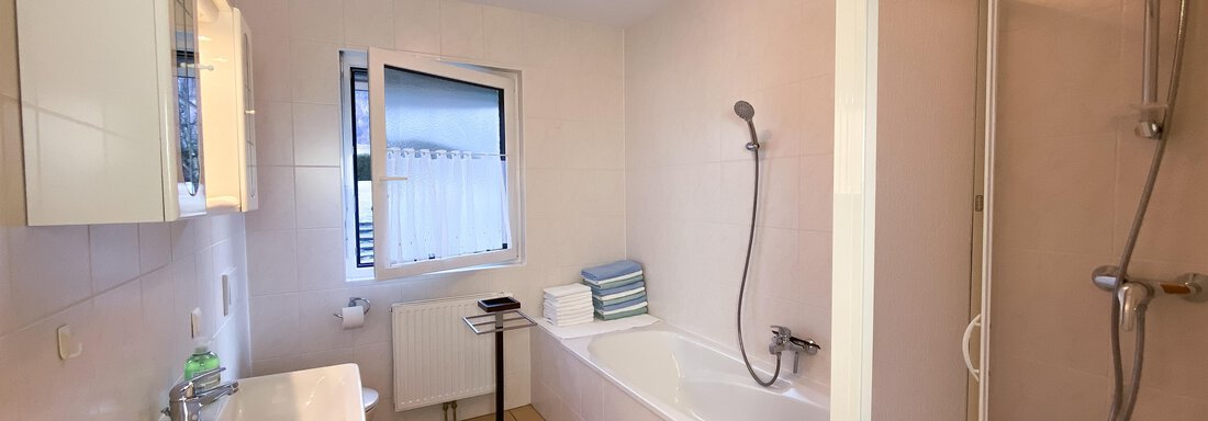 Ein modernes Badezimmer mit einer Badewanne und einer separaten Dusche. Große Fenster sorgen für viel Licht und eine angenehme Atmosphäre. - Ferienhaus Neurauter - Haiming