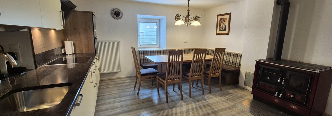 A modern kitchen with a large dining table and wooden chairs. The room is bright and cozy designed. - Landhaus Waldesruh - Haiming