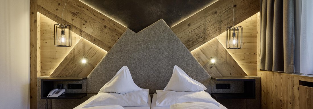 Doubleroom Schalfblick plus - Laurin 2150 | © Alpenhotel Laurin (CC C) A modern bedroom with two single beds and a stylish wood paneling. The soft lighting creates a cozy atmosphere. - Alpenhotel Laurin - Hochgurgl