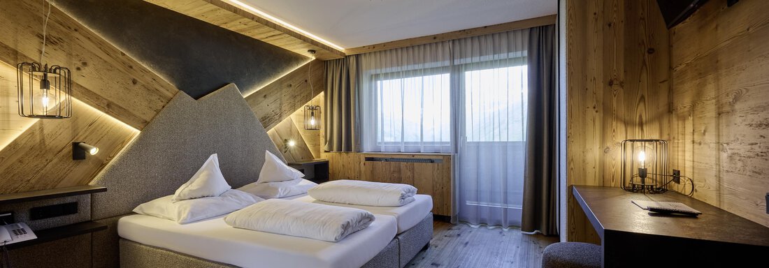 A modern hotel room with two single beds and wooden cladding. Large windows provide plenty of daylight and a view outside. - Alpenhotel Laurin - Hochgurgl