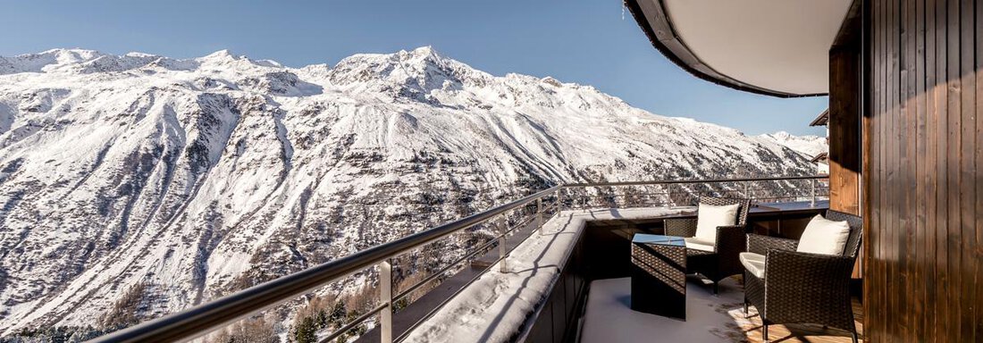 Balcony with a view of snow-covered mountains. Cozy seating invites you to relax. - Hotel Angerer Alm - Hochgurgl