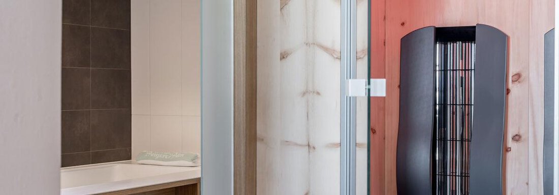A modern bathroom with a stylish whirlpool and wooden shelves. The walls are partially light and have a pleasant wood paneling. - Hotel Angerer Alm - Hochgurgl