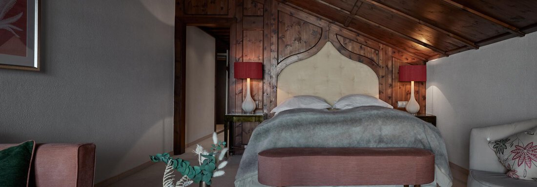 Ein gemütliches Schlafzimmer mit Holzwänden und einem stilvollen Bett. Das Zimmer ist elegant eingerichtet mit sanften Farben und verfügt über weiche Beleuchtung. - TOP Hotel Hochgurgl - Hochgurgl