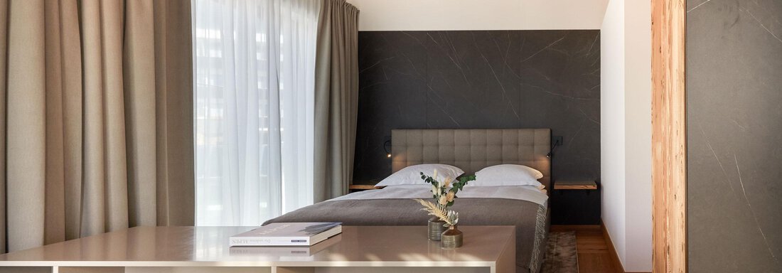 Ein modernes Schlafzimmer mit einem gemütlichen Bett und großen Fenstern. Die Holzdecke und die hellen Vorhänge sorgen für eine helle und freundliche Atmosphäre. - TOP Hotel Hochgurgl - Hochgurgl