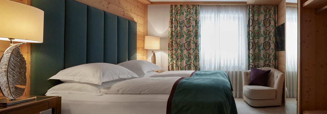 Cosy Ein elegantes Hotelzimmer mit einem großen Bett und gemütlicher Einrichtung. Holzverkleidete Wände und sanfte Beleuchtung schaffen eine entspannte Atmosphäre. - TOP Hotel Hochgurgl - Hochgurgl