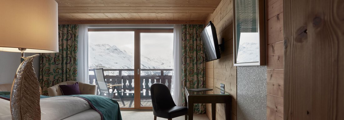 Comfort Room Ein stilvolles Hotelzimmer mit Holzverkleidung und einer gemütlichen Atmosphäre. Durch das Fenster sieht man eine schneebedeckte Landschaft. - TOP Hotel Hochgurgl - Hochgurgl
