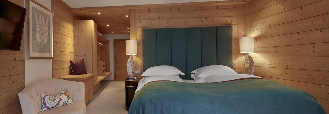 Ein gemütliches Hotelzimmer mit Holzvertäfelung und einem großen Doppelbett. Die sanfte Beleuchtung und die elegante Einrichtung schaffen eine entspannende Atmosphäre. - TOP Hotel Hochgurgl - Hochgurgl