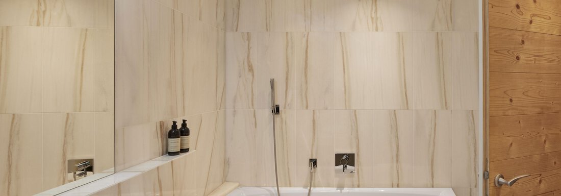 Ein elegantes Badezimmer mit modernem Design. Es enthält eine Badewanne, ein Waschbecken und stylische Pflegeprodukte. - TOP Hotel Hochgurgl - Hochgurgl