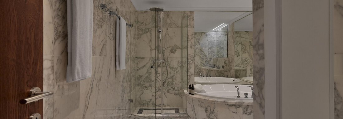 Ein elegantes Badezimmer mit marmorierten Wänden und einem großen Whirlpool. Das Ambiente ist modern und einladend. - TOP Hotel Hochgurgl - Hochgurgl