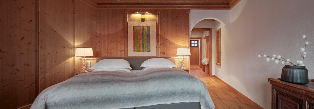 Ein modernes Schlafzimmer mit Holzverkleidung und einem großen Bett. Es gibt zwei Nachttische mit Lampen und einen gemütlichen Wohnbereich. - TOP Hotel Hochgurgl - Hochgurgl