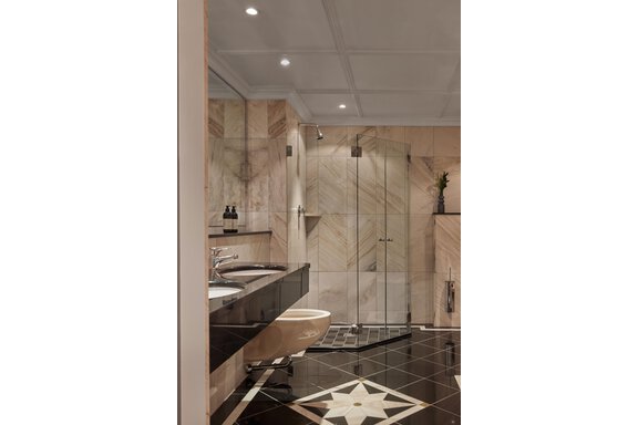 Ein modernes Badezimmer mit eleganten Marmorwänden und klaren Glasduschwänden. Der Boden ist mit einem auffälligen Muster in Schwarz und Weiß gestaltet. - TOP Hotel Hochgurgl - Hochgurgl