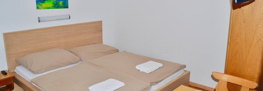 A simple bedroom with a double bed, two pillows, and fresh towels. A table and a television are also available. - Haus Maria - Hochsölden