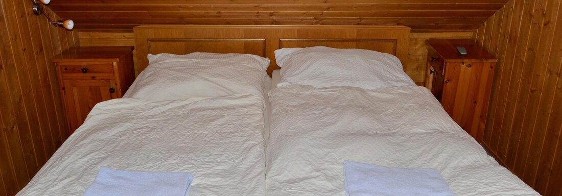 A cozy bedroom with a double bed and wood paneling. Next to the bed are two nightstands. - Haus Maria - Hochsölden