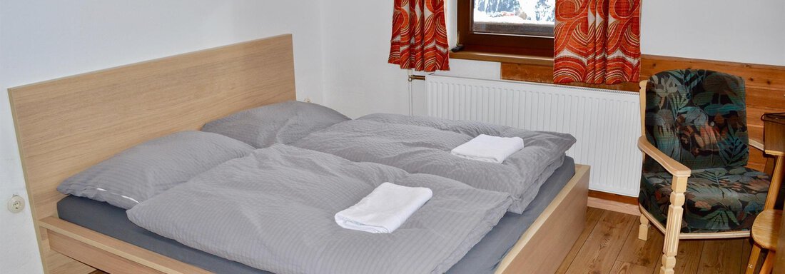 A cozy bedroom with a double bed and modern wood design. Large windows provide plenty of daylight and an inviting atmosphere. - Haus Maria - Hochsölden