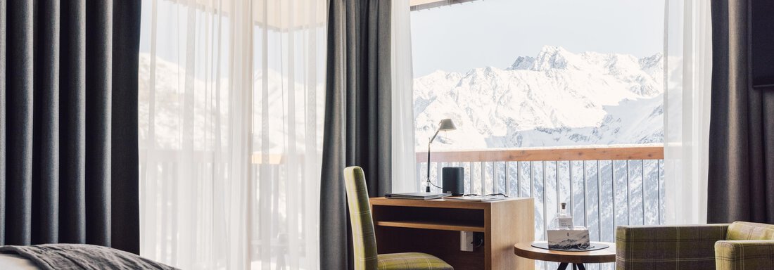 A modern hotel room with a view of the mountains.  
Large windows let in plenty of light and offer a magnificent view. - 4 * Superior Hotel Schöne Aussicht - Hochsölden
