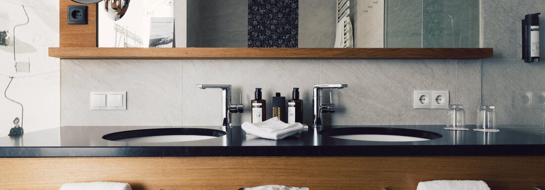 A modern bathroom with double sink and wooden details. The amenities include toiletries and fresh towels. - 4 * Superior Hotel Schöne Aussicht - Hochsölden