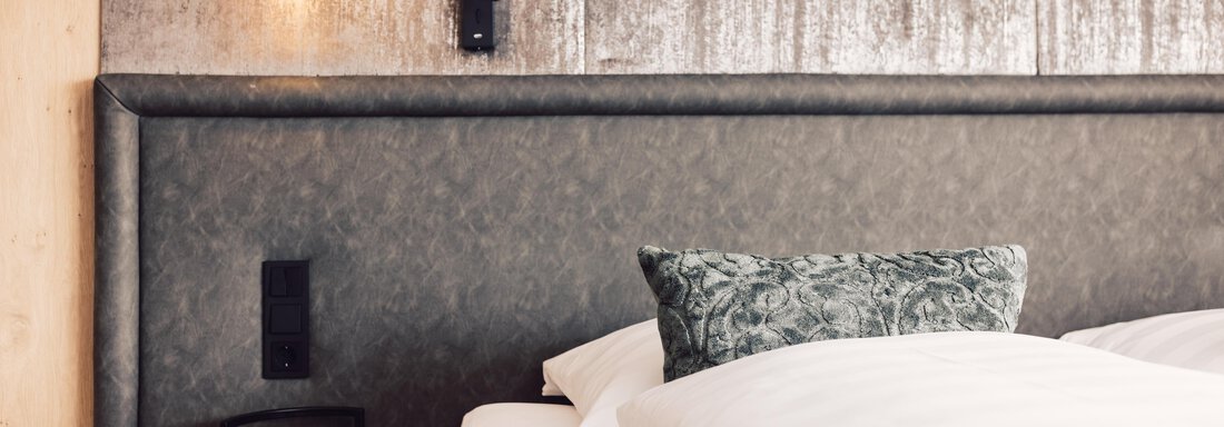 A modern bedroom with an elegantly upholstered headboard and stylish cushions. Soft lighting creates a cozy atmosphere. - 4 * Superior Hotel Schöne Aussicht - Hochsölden